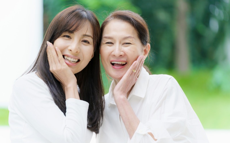 中年女性と若い女性が頬肌を手で抑え嬉しそうにしている